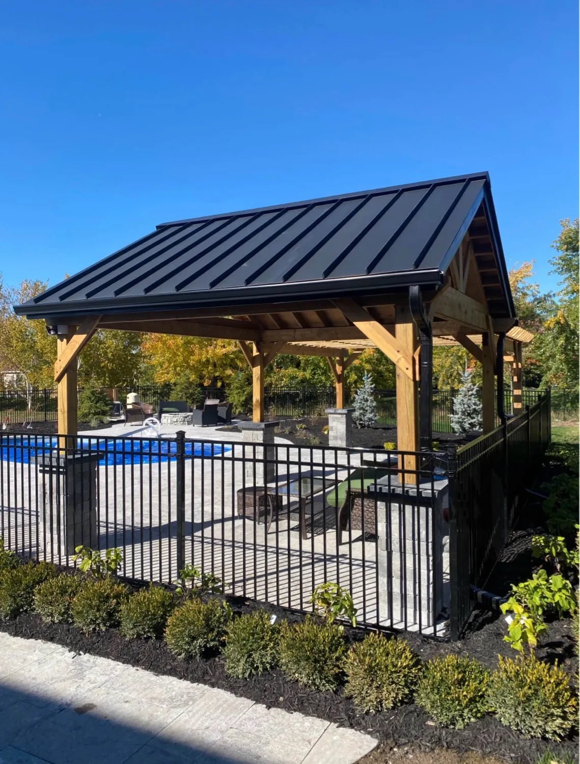 Black standing seam metal roof installation on backyard pavilion overlooking pool — D&D Exterior Finishing Kitchener-Waterloo