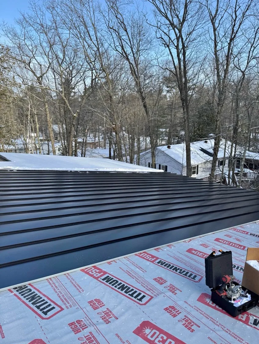 Black standing seam metal roof installed over Titanium PSU underlayment during winter project in Waterloo Region