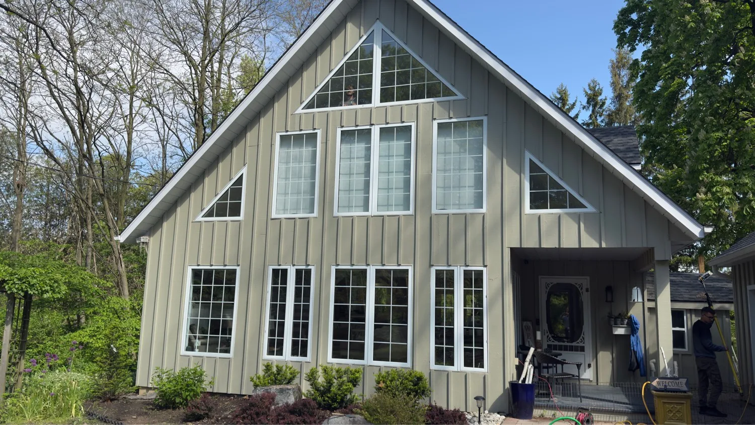 Full board-and-batten facade with custom triangular gable windows and grid-pattern glazing — D&D Exterior Finishing