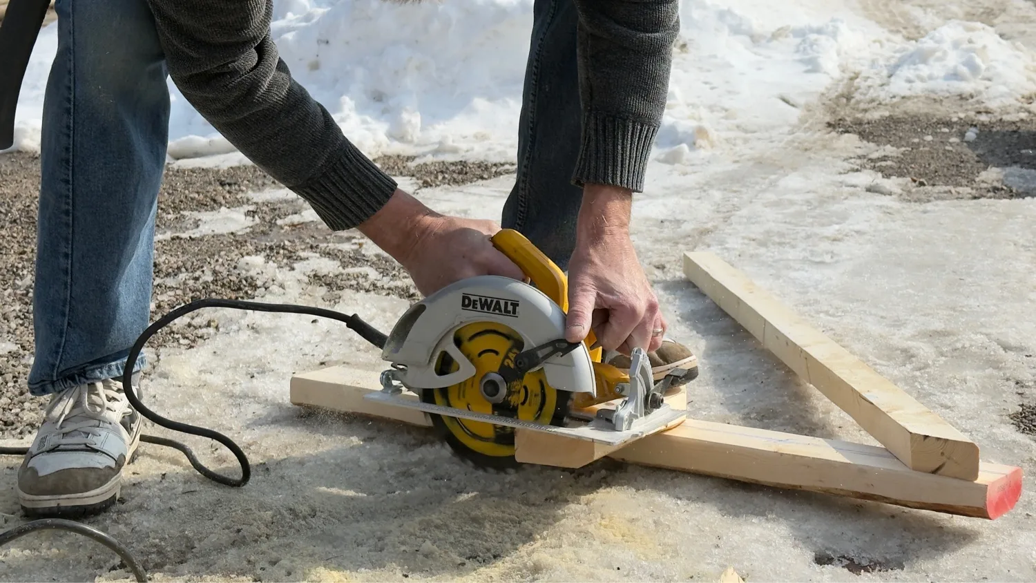 D&D Exterior Finishing carpenter cutting pressure-treated lumber with DeWalt circular saw — winter deck build