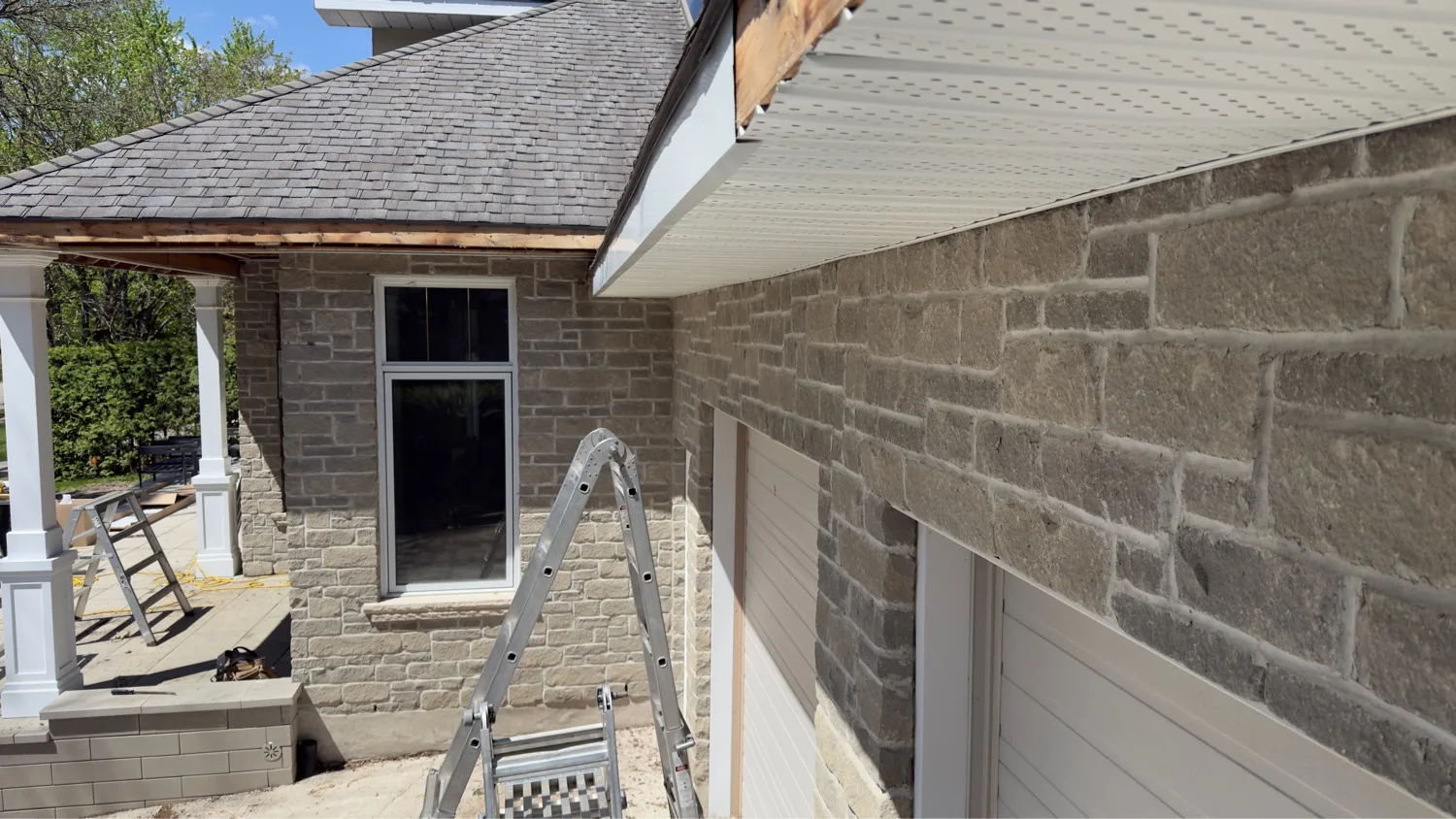 In-progress fascia and vented soffit install showing exposed wood subfascia on stone double-garage home in Waterloo Region