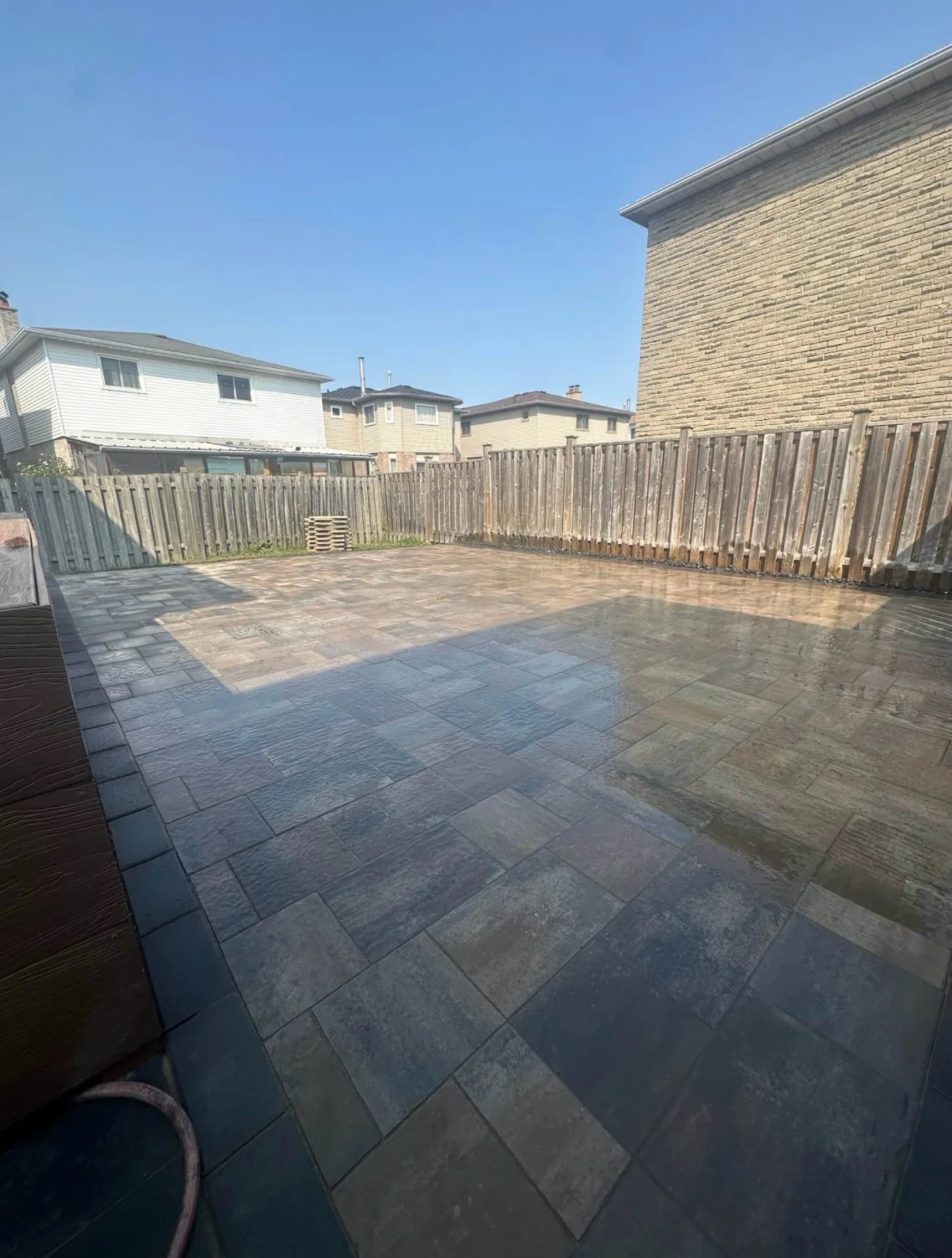 Wet backyard interlock patio with mixed-tone pavers — Waterloo Region installation by D&D Exterior Finishing