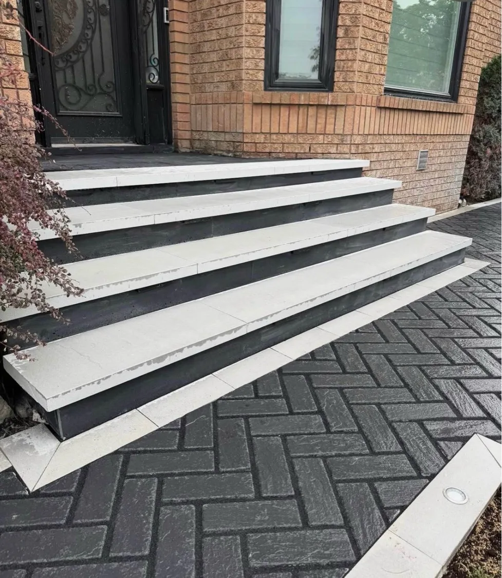 Custom interlock steps with white stone caps over charcoal herringbone driveway — D&D Exterior Finishing