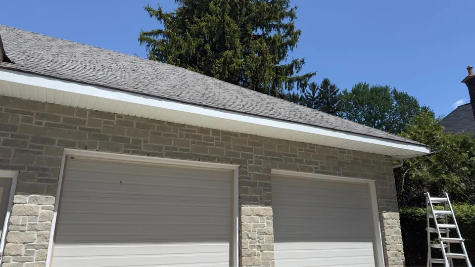 White fascia and vented soffit along a stone garage roof