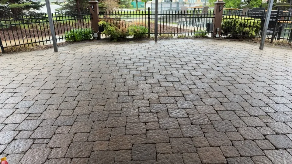 Interlocking patio pavers with a fence and lawn beyond