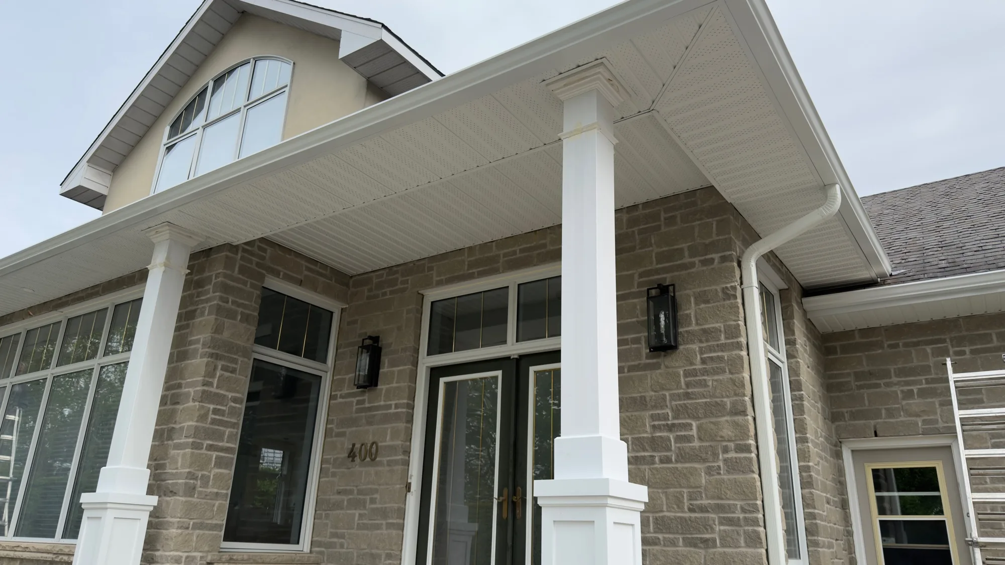 White vented soffit installation on stone home with columns — D&D Exterior Finishing Kitchener-Waterloo