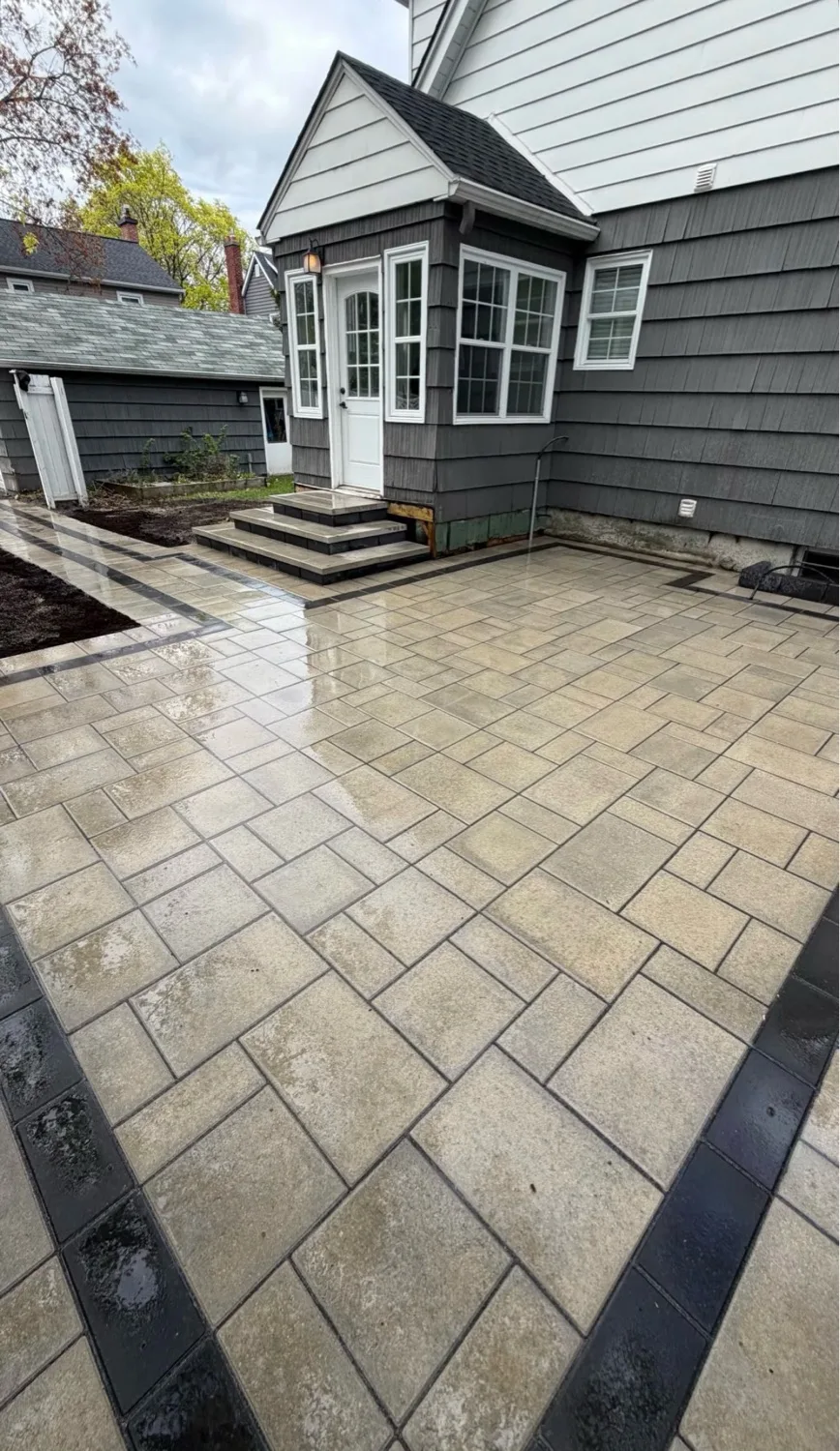 Cream rectangular paver patio with charcoal accent strip and black border surrounding shake-sided home in Kitchener — D&D Exterior Finishing